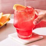 Rode alcoholvrije mocktail met grapefruit en ijs, geserveerd op een onderzetter
