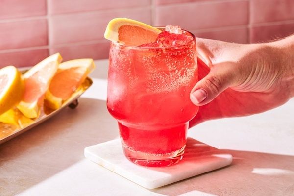 Rode alcoholvrije mocktail met grapefruit en ijs, geserveerd op een onderzetter