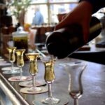 Donkere drank wordt in kleine glaasjes op een bar geschonken