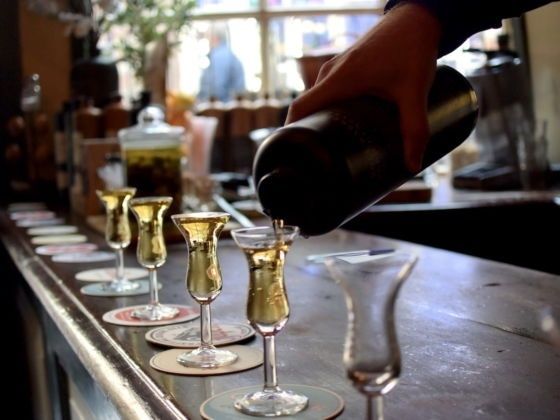 Donkere drank wordt in kleine glaasjes op een bar geschonken